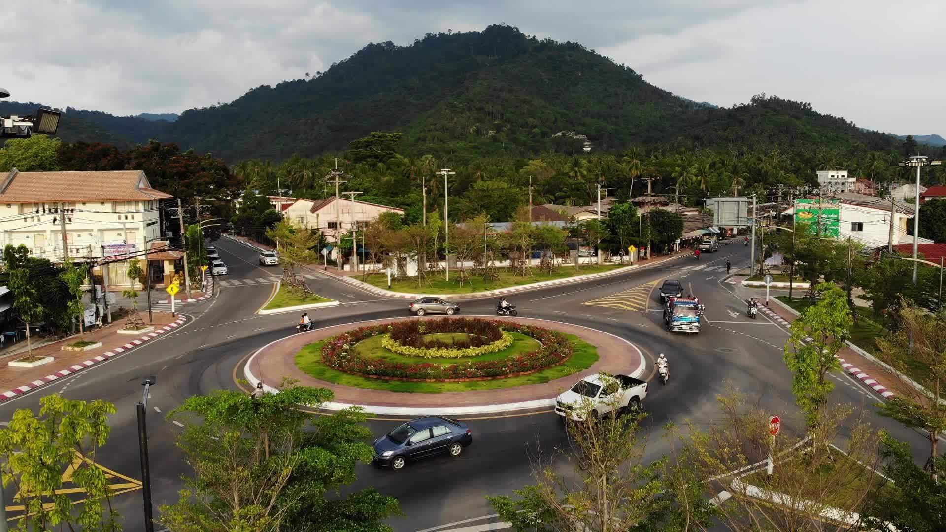 汽车骑在丛林附近小镇的环形十字路口泰国苏梅岛小镇中部视频的预览图