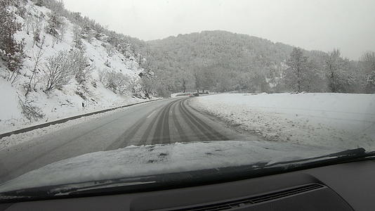 在冬雪中驾驶汽车在雪覆盖的雪山路上驾驶视频的预览图