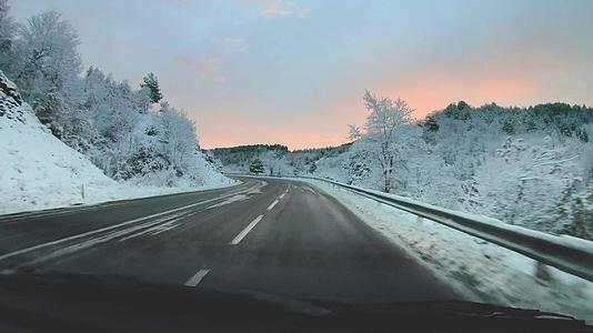 冬天山路雪在日出时在山区和丘陵附近的冬天快速移动视频的预览图