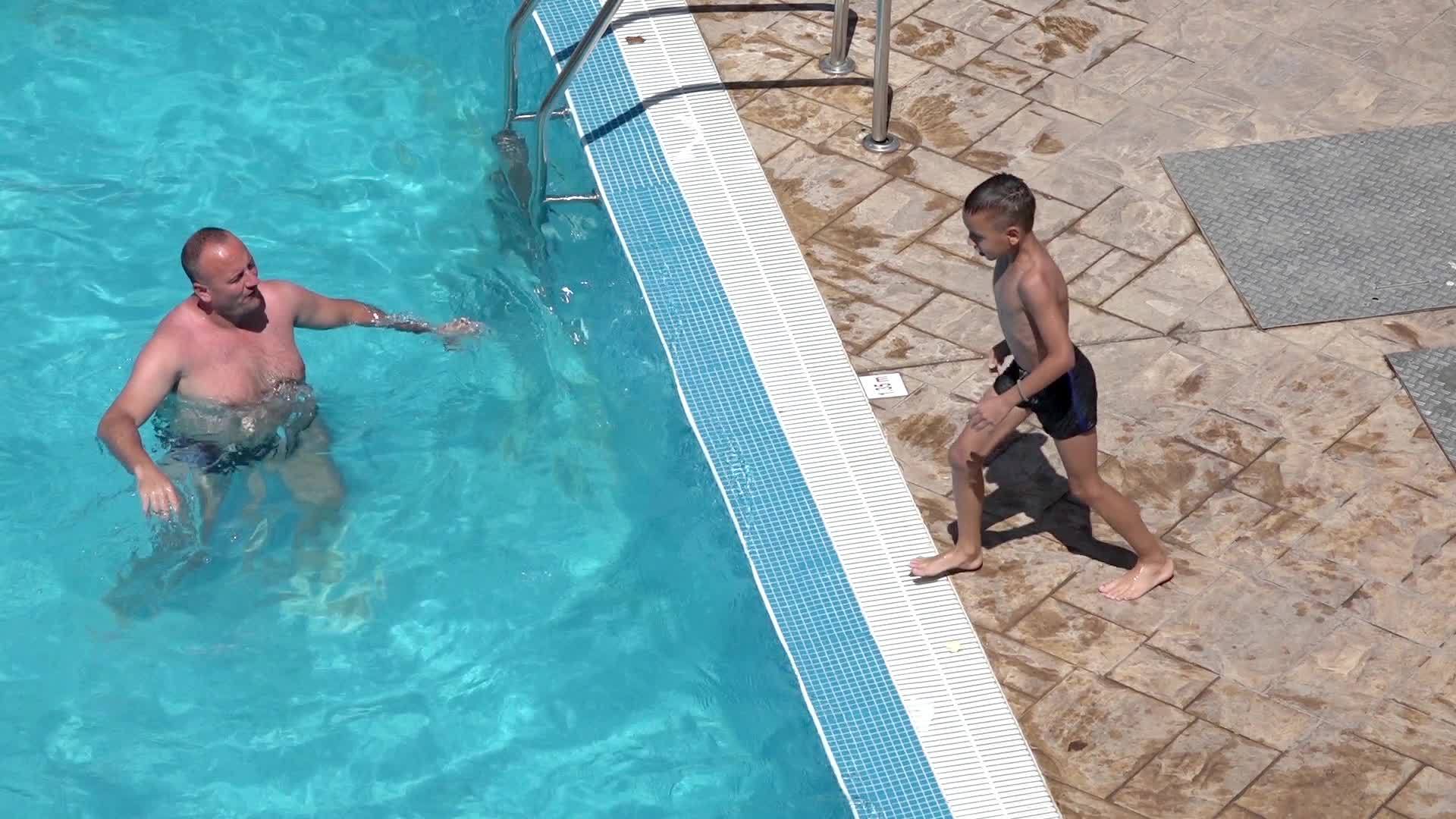 在游泳池里父亲学会了儿子跳过浮云慢慢移动视频的预览图