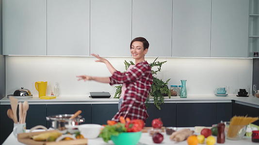 在现代厨房为朋友或家人做饭时他们穿着长袍留着卷发视频的预览图