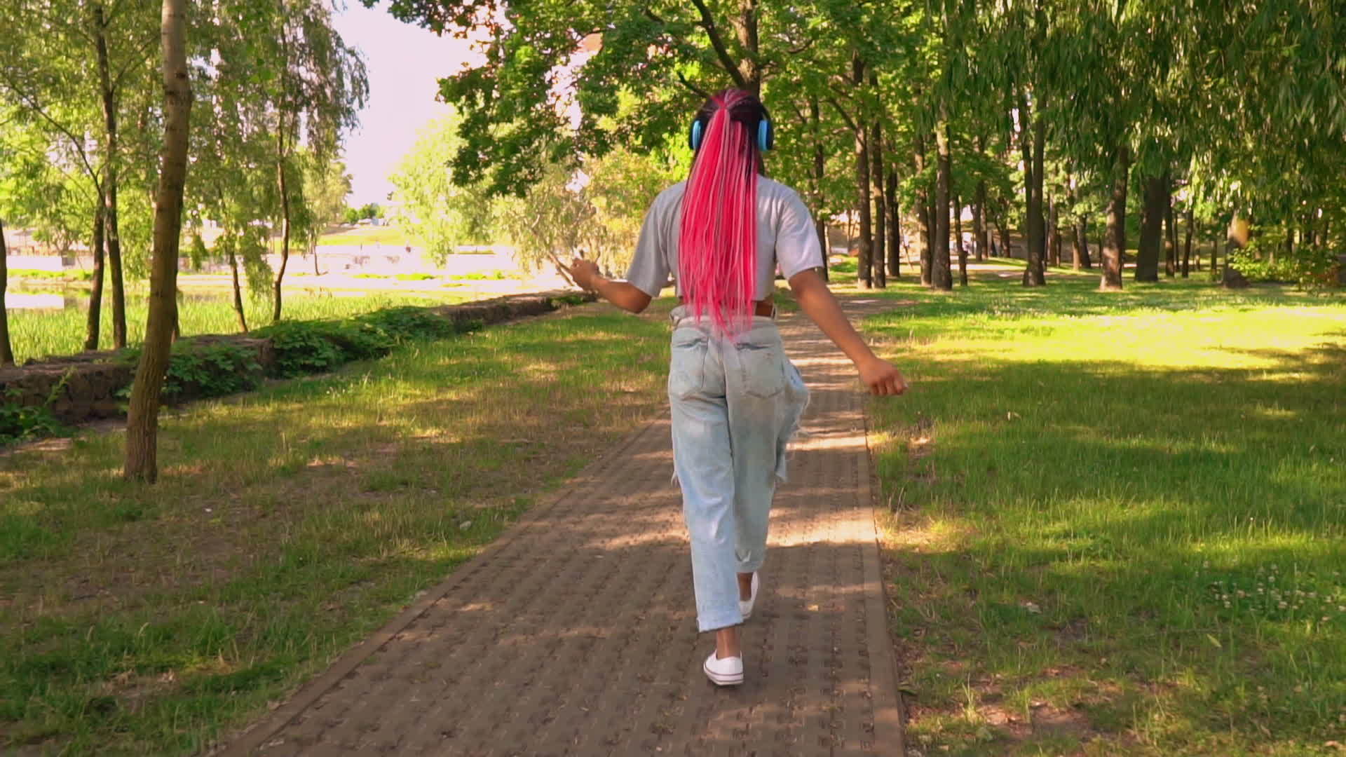 快乐的女人戴着耳机在城市里散步视频的预览图