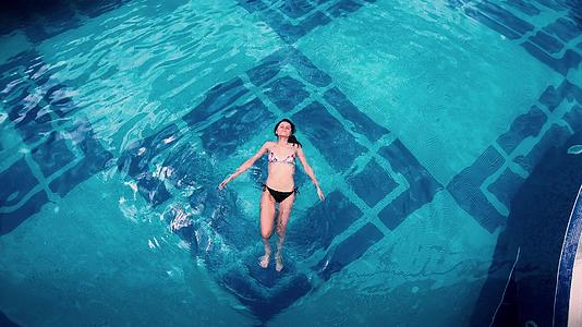 美丽的年轻女子她的身体被压在水面上躺在清澈的池塘里视频的预览图