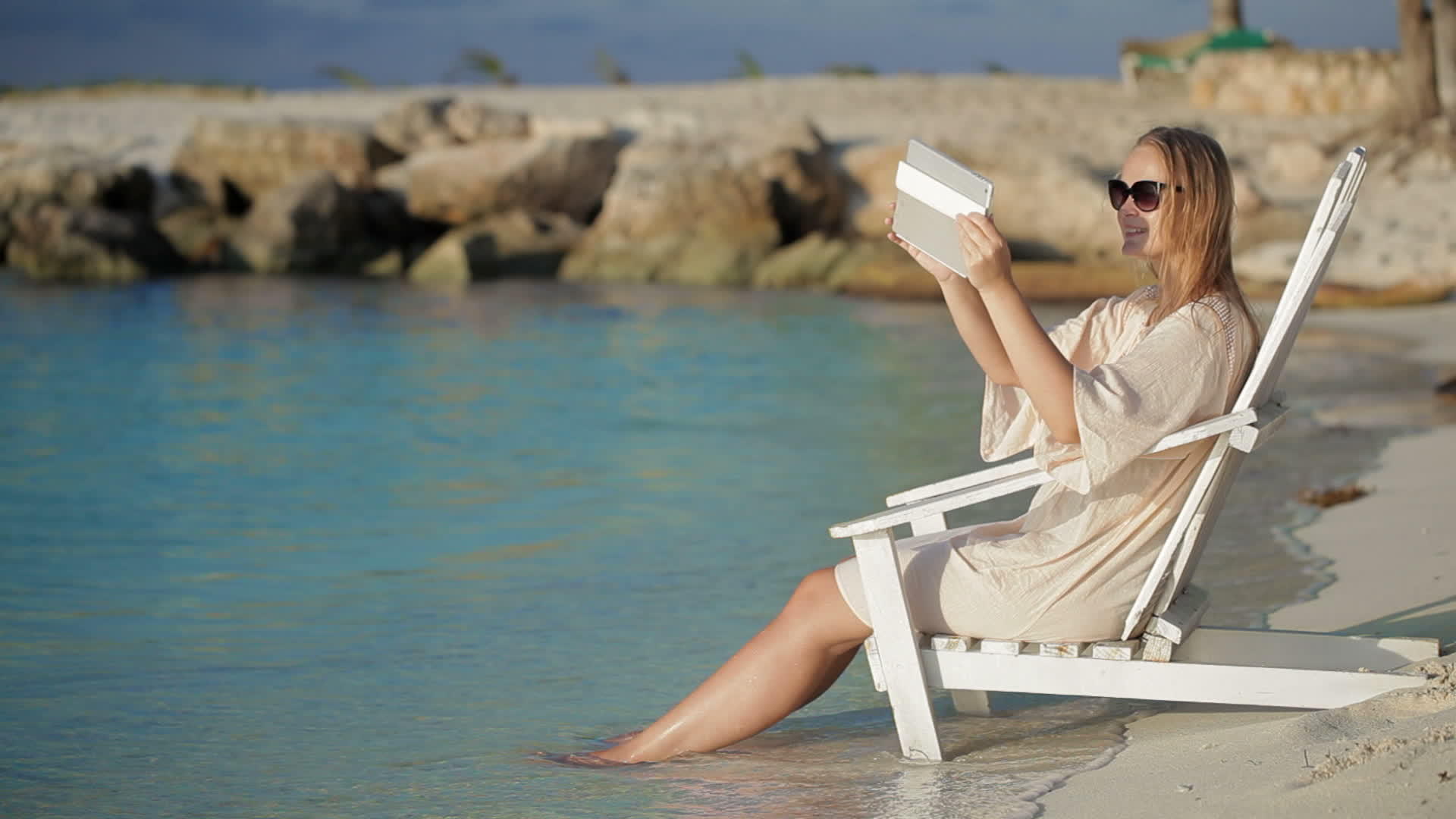 在海滩的甲板椅上拍摄海景照片的女性床垫视频的预览图
