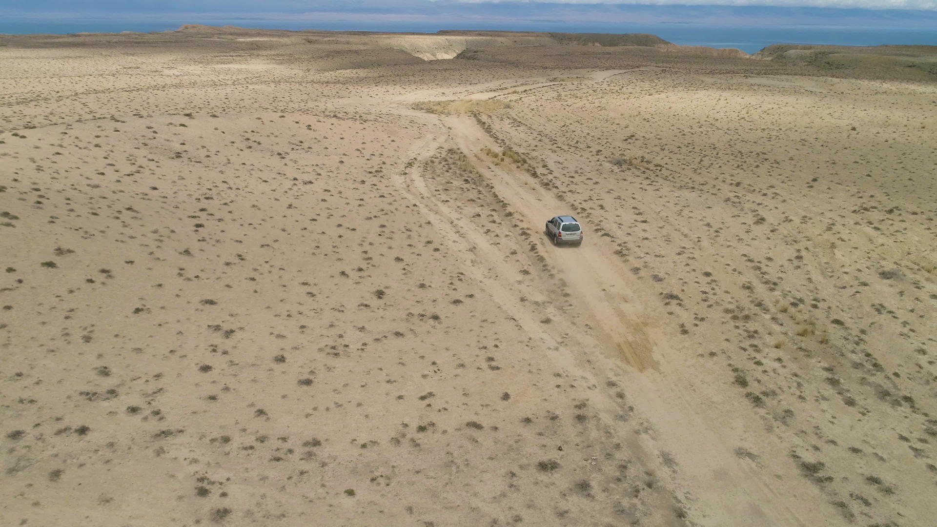 SUV汽车在沙滩荒地上行驶观察沙漠景观和湖岸背景视频的预览图
