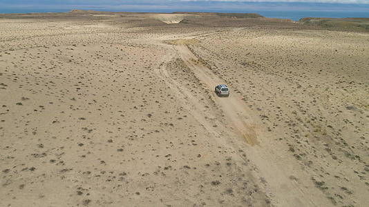 SUV汽车在沙滩荒地上行驶观察沙漠景观和湖岸背景视频的预览图