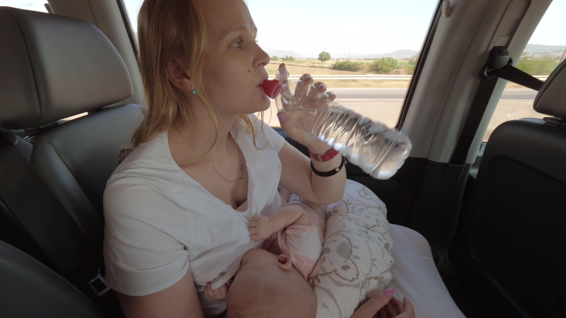母亲、哺乳婴儿和流动汽车上的饮用水视频的预览图