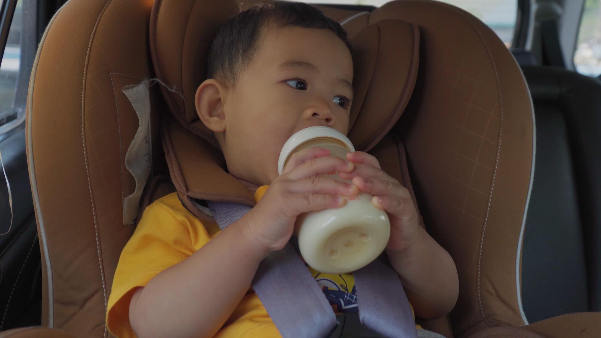 男孩在车里的座位上喝瓶装牛奶视频的预览图