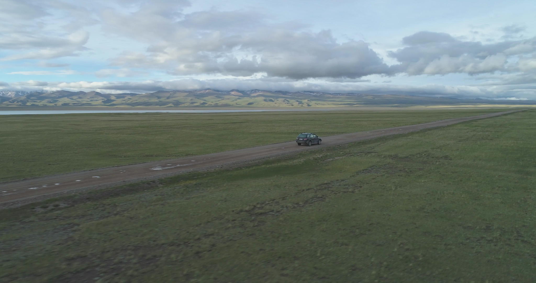 SUV夏天汽车在碎石路和湖岸的山丘上观察无人驾驶视频的预览图