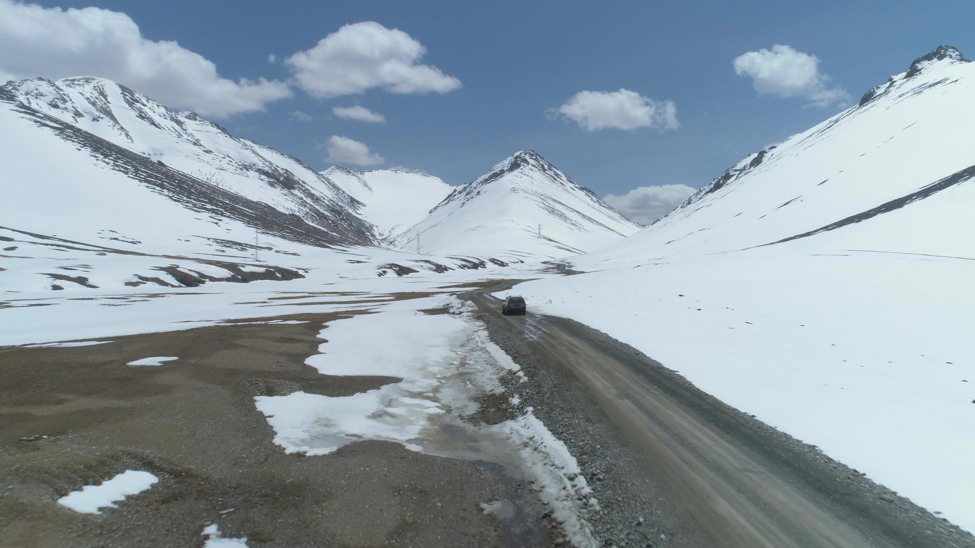 在阳光明媚的日子里汽车在雪山的高海拔砾石路上行驶视频的预览图