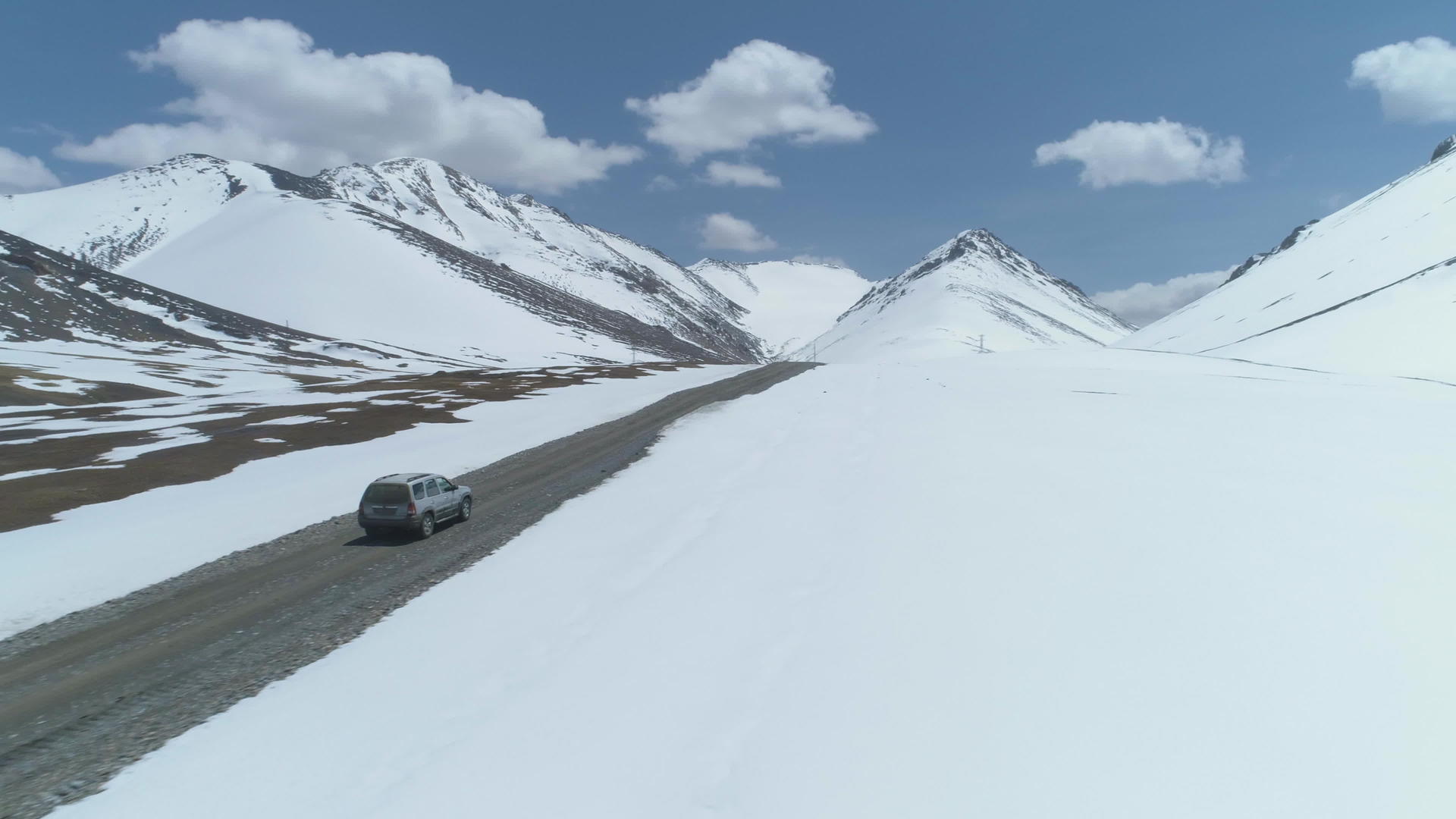 SUV汽车在阳光明媚的雪山上汽车在空中观察无人机视频的预览图