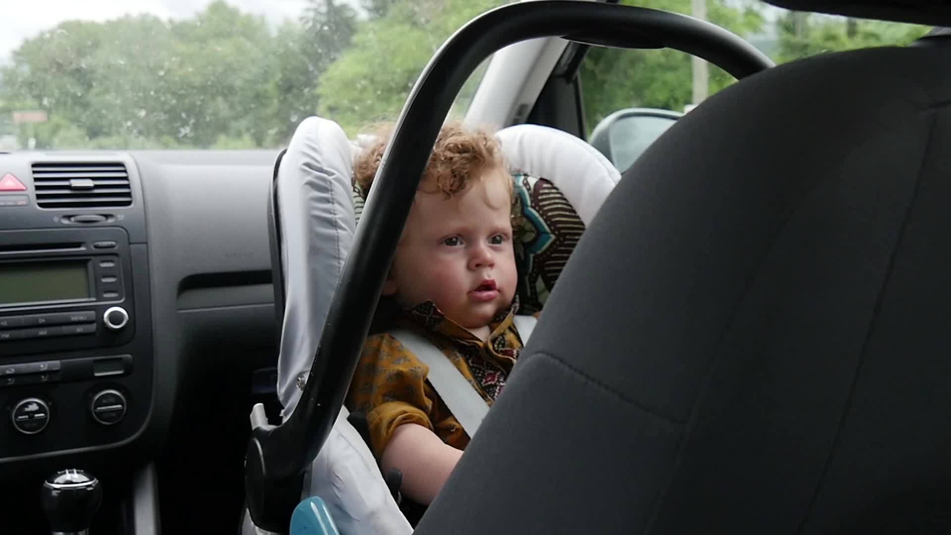 一个小男孩的肖像坐在汽车座椅上视频的预览图