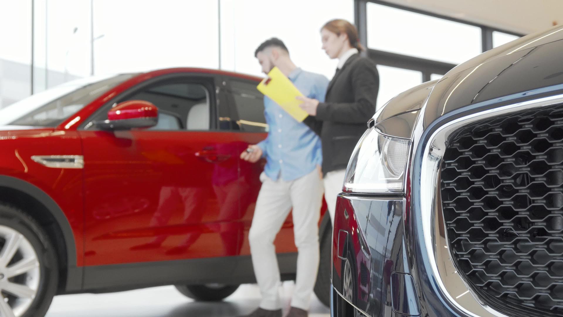 销售人员和男性客户在汽车经销商检查汽车视频的预览图