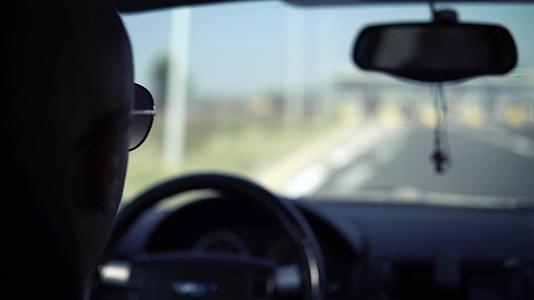 戴着太阳镜的人在公路上的工作站附近开车视频的预览图
