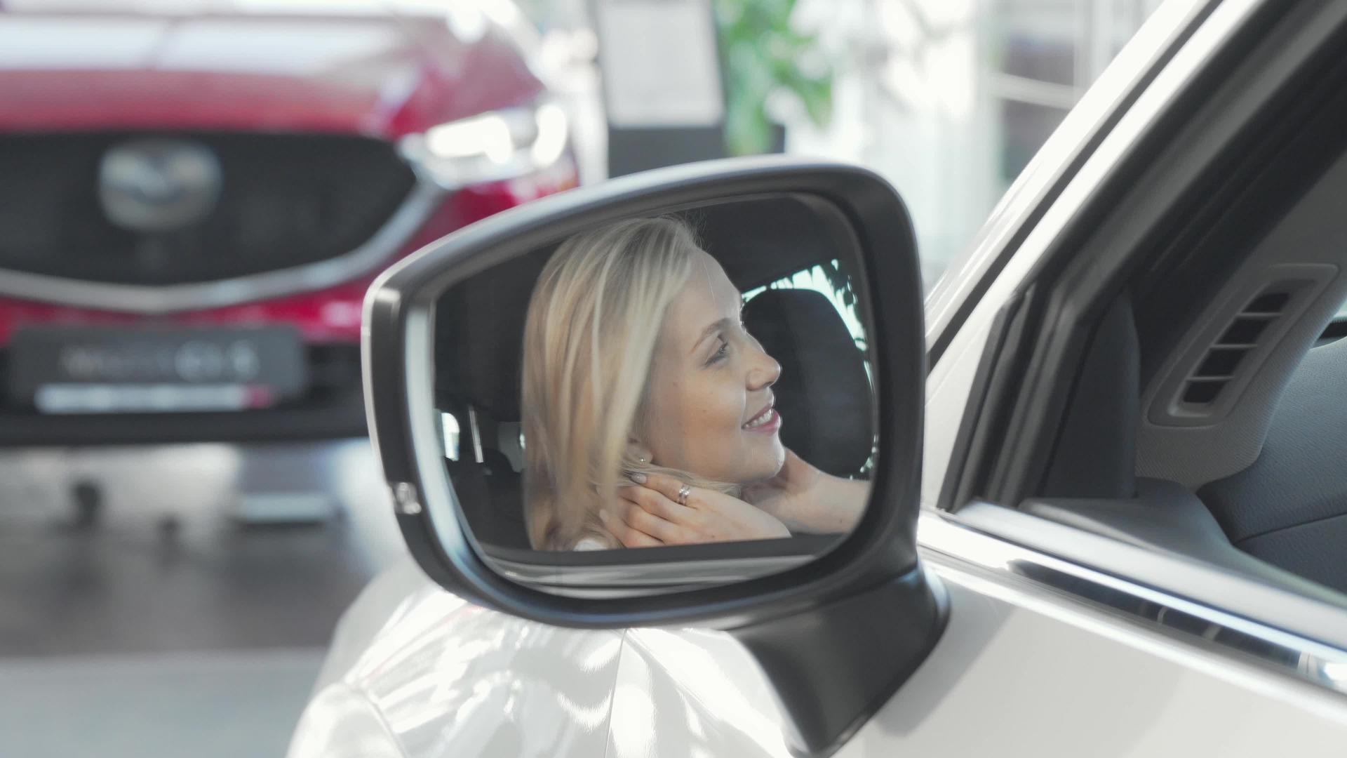 这位美丽快乐的女士在镜头前对着车的侧镜微笑视频的预览图