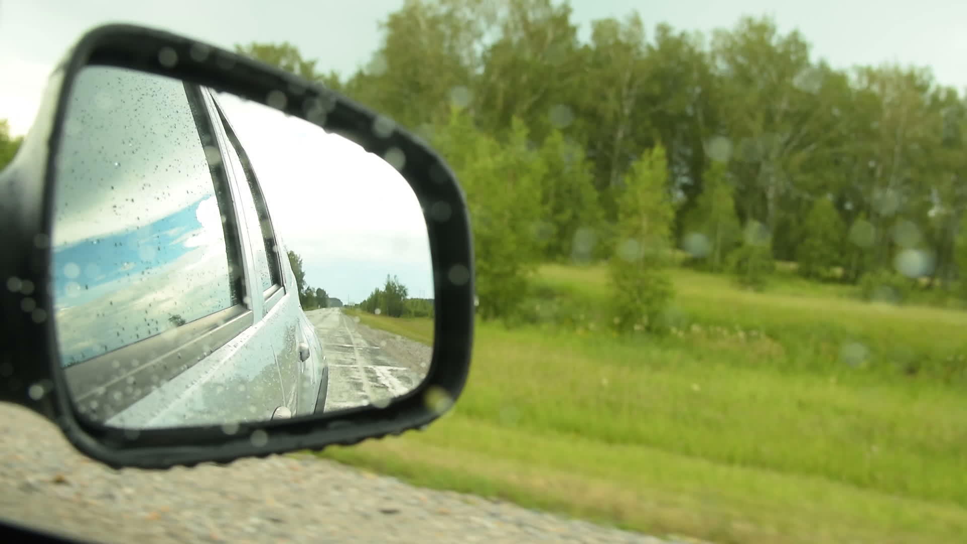 一面镜子反射在农村雨天驾驶汽车的侧视镜后面视频的预览图