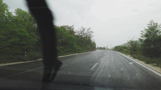 在不好的天气湿透风屏有滴水和反射器在雨中行驶视频的预览图