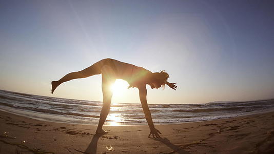 面对沙滩上缓慢的日落动作的柔性运动视频的预览图