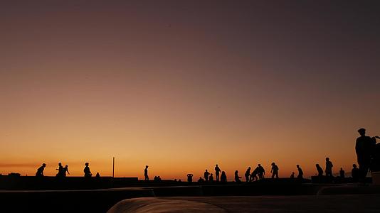 年轻的跳跃滑板手骑着长长的夏季日落背景视频的预览图