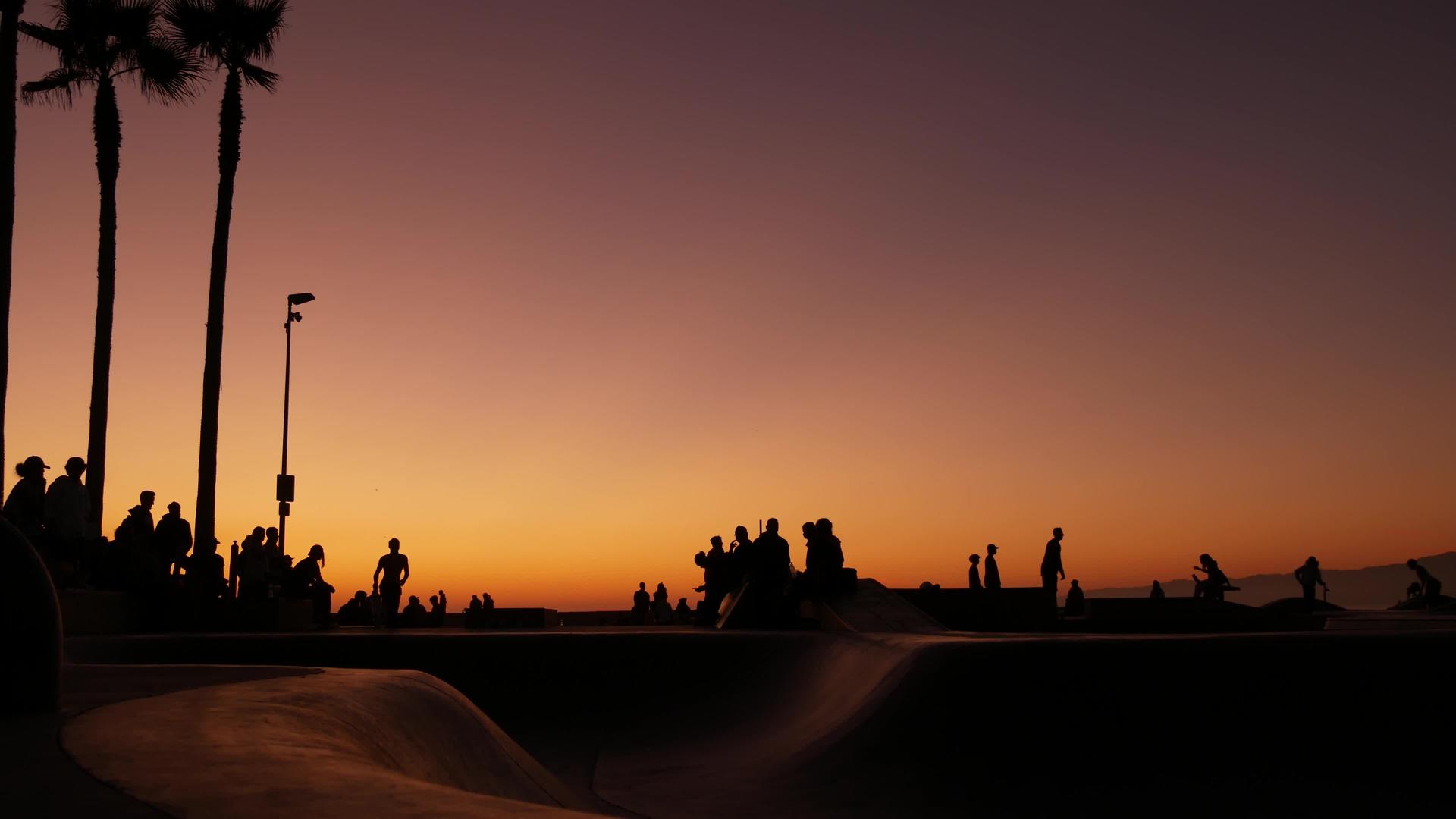 年轻的跳跃滑板手骑着长长的夏季日落背景视频的预览图