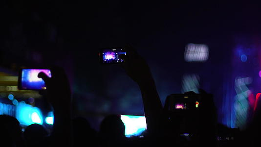 人群中抽象的剪影师举手跳舞抱着智能手机失焦视频的预览图