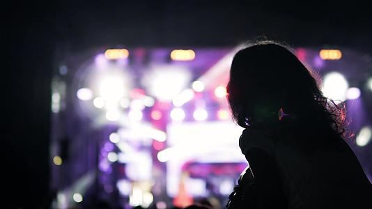 在户外音乐节的公共音乐会上一个卷发的女孩坐在肩上视频的预览图
