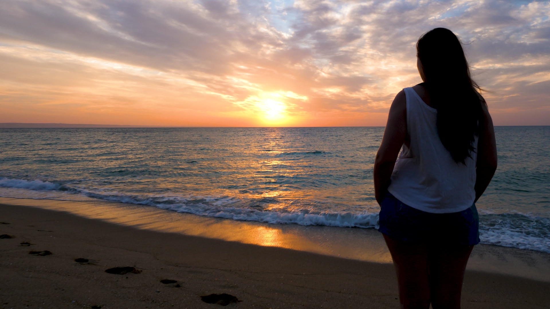 在海滩上女人的脚影被放大欣赏日出的风景视频的预览图