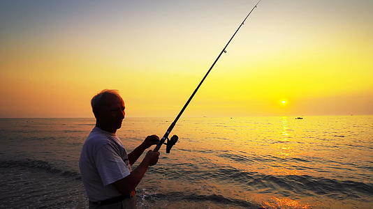 夏天当海上日落时用棍子钓活跃的渔民视频的预览图