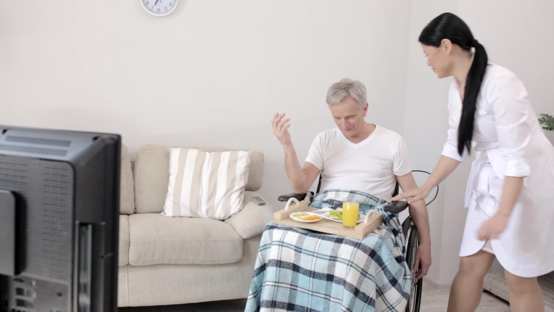 迷人的护士为坐在轮椅上的残疾人带来早餐视频的预览图