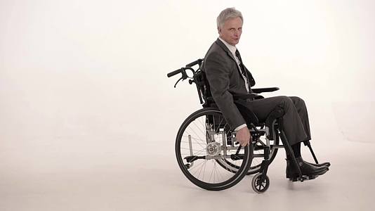 坐在轮椅上的瘫痪商人工作室拍摄视频的预览图