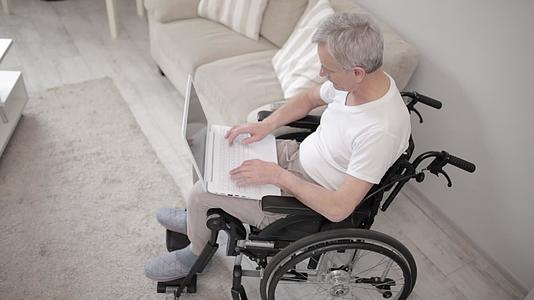 轮椅残疾人在笔记本电脑上打字视频的预览图