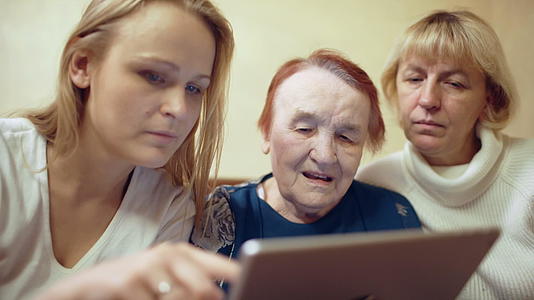 床垫上的妇女向母亲和祖母展示照片或视频视频的预览图
