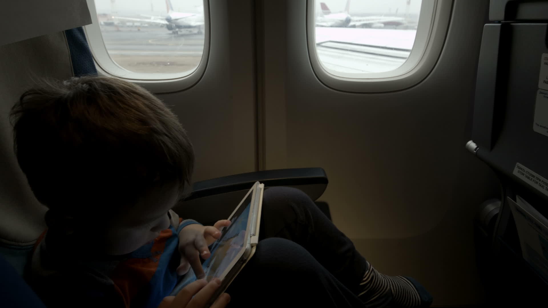 男孩坐在飞机上使用平板电脑视频的预览图