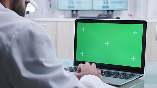 医生在笔记本电脑上用绿色屏幕工作视频的预览图