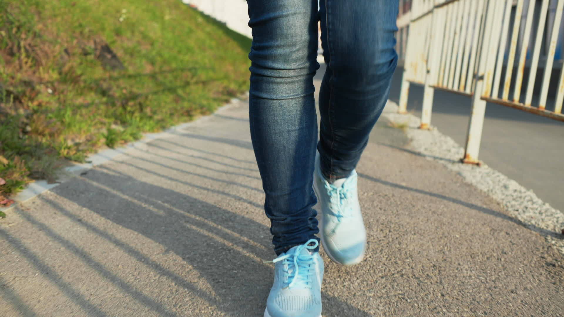 女性在阳光明媚的城市慢动作穿着蓝色牛仔裤和运动鞋视频的预览图