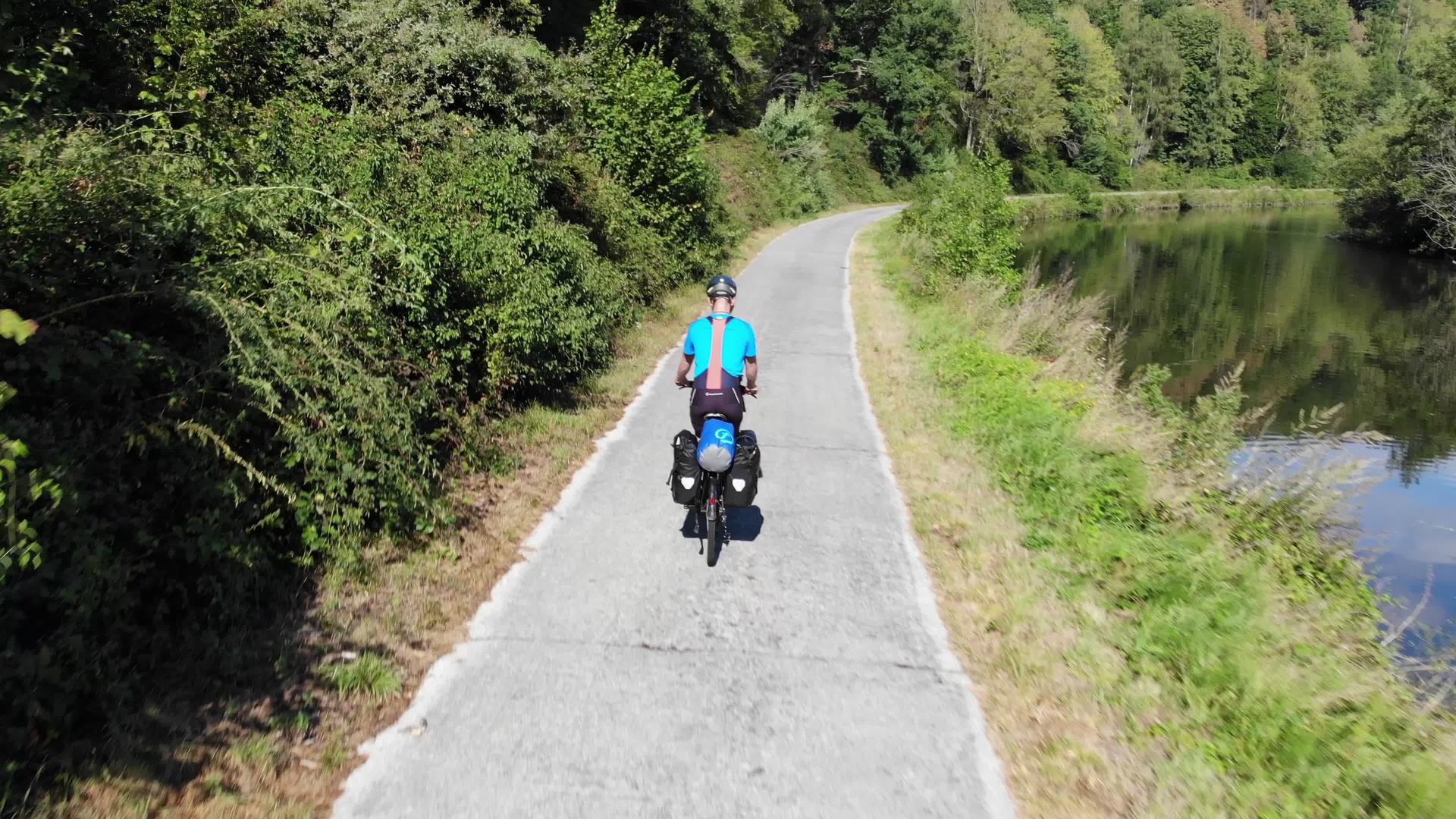 骑自行车的人从后面穿过时的铺好的路上从后面穿过森林视频的预览图