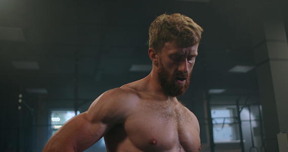 穿着运动服的年轻强壮的男人站在健身房的窗户前视频的预览图