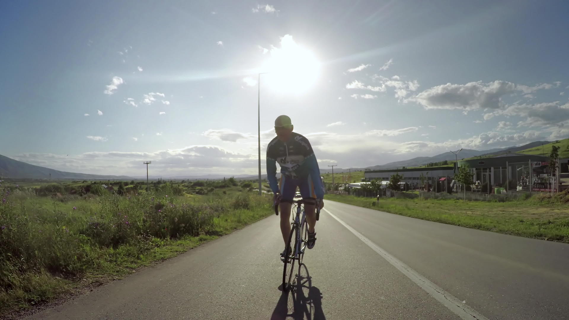 骑自行车的人在路边运动中尽力在山上赛跑 背景是日落 视频的预览图