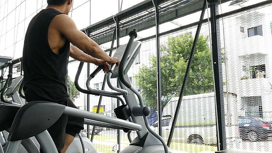 在健身中心锻炼亚洲运动员的年轻肌肉男在健身房锻炼椭圆视频的预览图