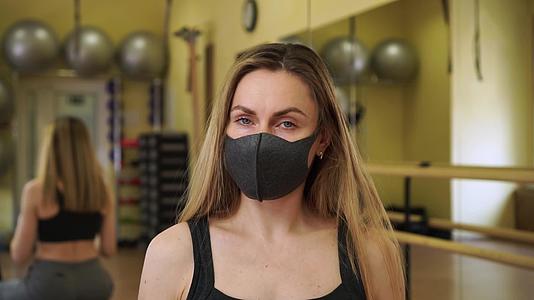 美丽的女性健身教练脱下两个医用防护口罩可以正常工作视频的预览图