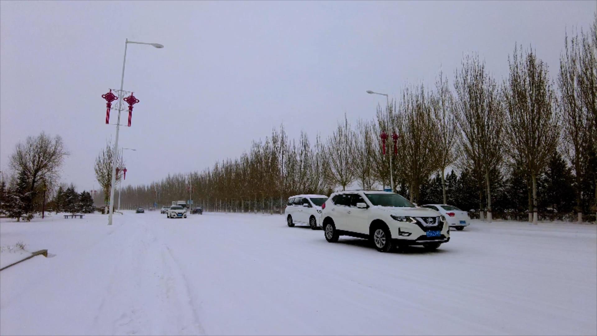 4k实拍北方飘雪的冬季街道上缓慢行驶的汽车视频的预览图
