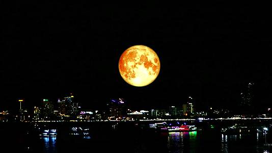 满月的鲜血笼罩着夜晚的城市和海上的船只视频的预览图