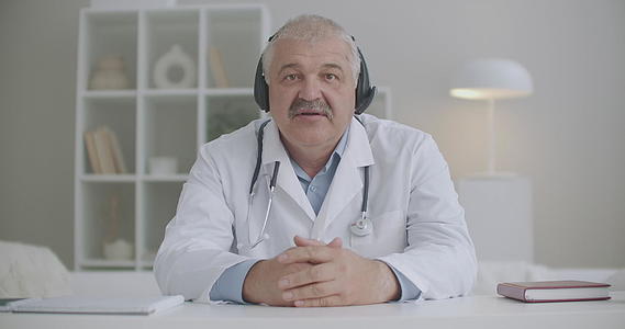 男性心脏病医生坐在诊所办公室用笔记本电脑在线咨询视频的预览图