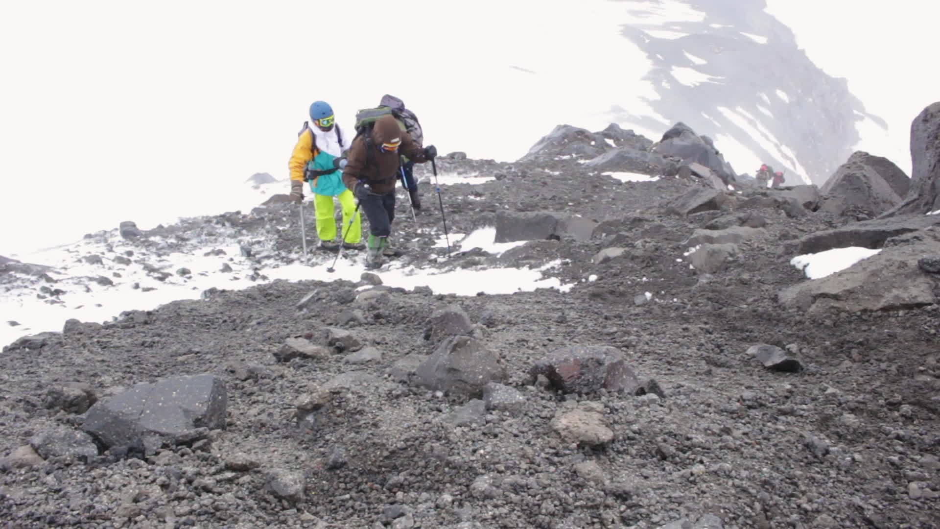 一群背着背包的登山者在山上的石头上行走他们用远足杆视频的预览图
