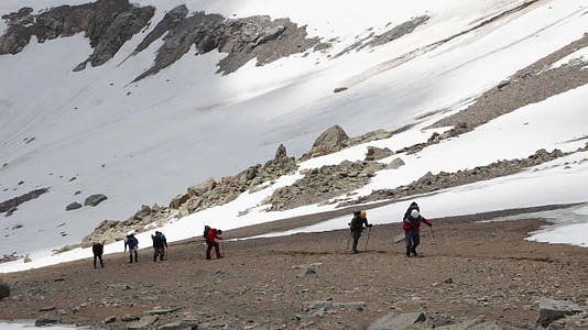 一群疲惫的徒步旅行者正在山上用徒步旅行杆和头盔山视频的预览图