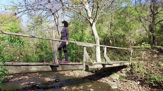 女运动员在森林中穿过木桥Stadicam漫步拍摄视频的预览图