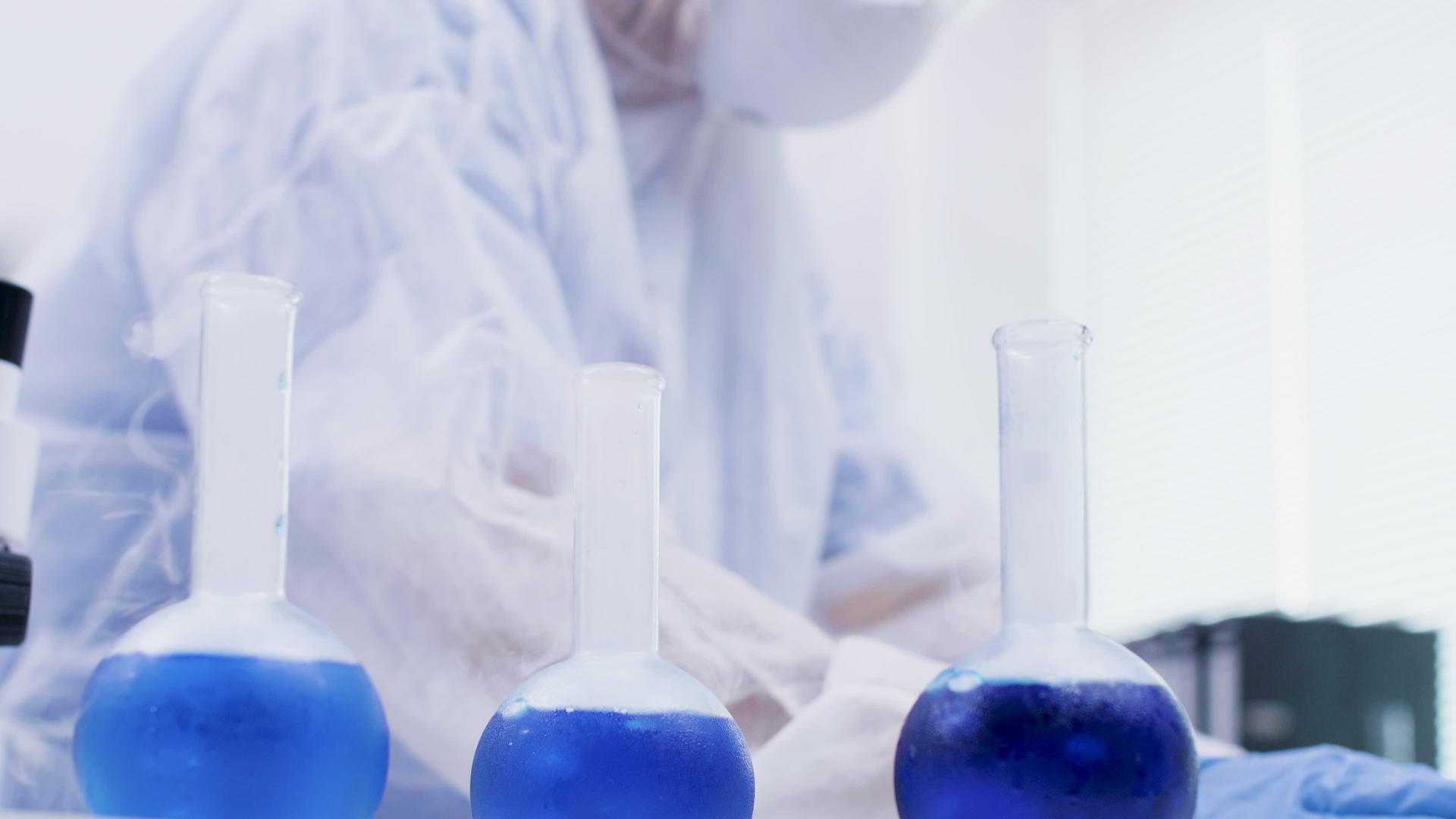 女性科学家持有蓝色溶液并在研究实验室中含有试剂视频的预览图