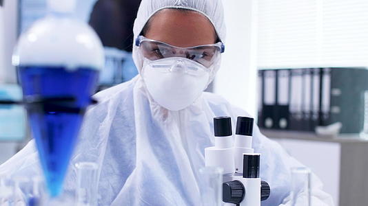 女性科学家在覆盖设备中持有并观察含有蓝色液体的乳管视频的预览图