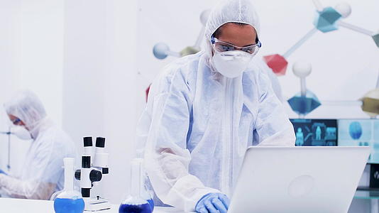 女科学家站在现代化学实验室里穿着全套设备站在电脑里视频的预览图
