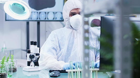 生物学家穿着防护服戴着口罩在显微镜上观察视频的预览图
